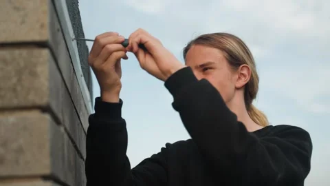 Skilled individual carefully fixing hook onto wall roof surface. Casual worker Stock Footage 332365944