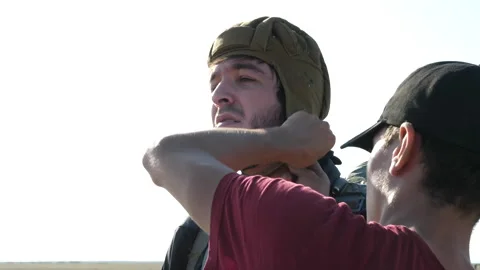 Skilled instructor helps man tighten green parachute helmet Stock Footage 144346489