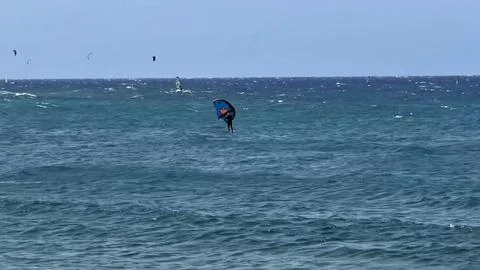 A Skilled Kite Surfer in Action Riding the Vibrant Ocean Waves Under a Bright Stock Photos
