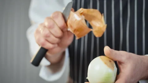 Skilled line cook uses precise technique to peel onion over cutting board Stock Footage 324576010
