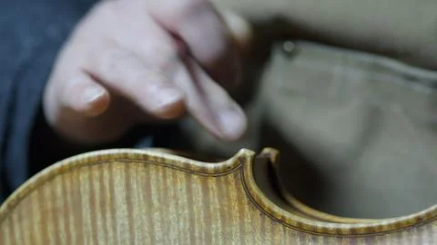 Skilled luthier hand applying protective varnish layer on violin body, care.. Stock Photos