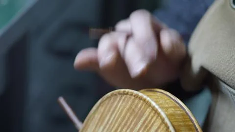 Skilled luthier hand applying protective varnish layer on violin body, care.. Stock Photos