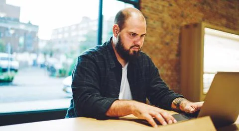 Skilled male freelancer with beard using laptop computer for online messaging Stock Photos