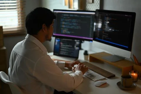 Skilled male programmer working with coded data on computer screen in dark room Stock Photos