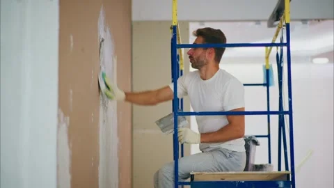 Skilled Man on Scaffold Applying Fresh Plaster to Drywall; Emphasizing the Art Stock Footage 316061813