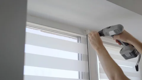 Skilled man is spinning screw for fixing fastener on window, using recharged Stock Footage 88084638
