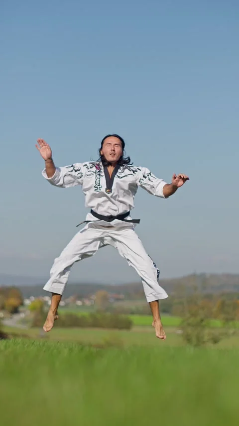A Skilled Martial Artist Performing a Dynamic Jump in the Air within a Scenic Stock Footage 302656366