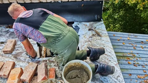 Skilled master bricklayer working on a residential roof, renovating a chimney Stock Footage 329004038
