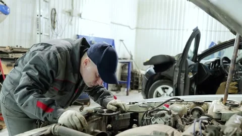 Skilled mechanic diagnosing automotive engine problem, wearing protective Stock Footage 338217707