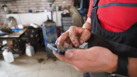 Skilled mechanic interacts with smartphone, showcasing hands covered in grease Stock Footage 324501187