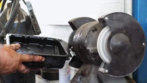 Skilled mechanic using a grinding machine to polish an engine oil pan Stock-Footage 324501627