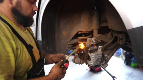 Skilled mechanic using a torch to heat brake components, intricate process Stock Footage 324500970