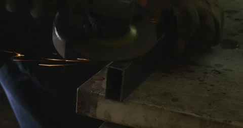 Skilled metalworker using an angle grinder to smooth the edge of a rectangular 動画素材 333232436