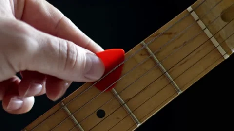 A skilled musician's hand expertly inserts a pick between the strings on a Stock Footage 231382337