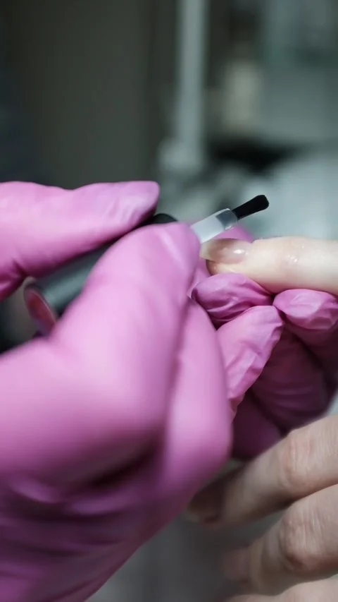 Skilled nail technician applying nail polish or base coat, making a manicure. Stock Footage 326251553