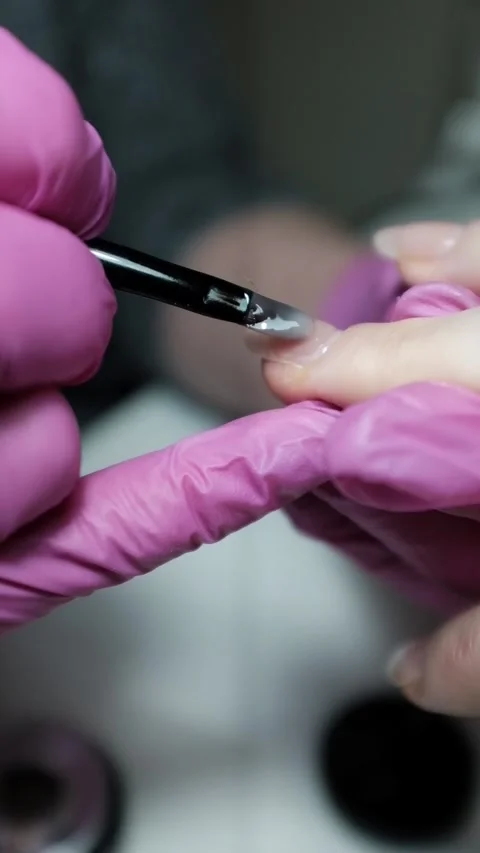 Skilled nail technician applying nail polish or base coat, making a manicure. Stock Footage 326251597