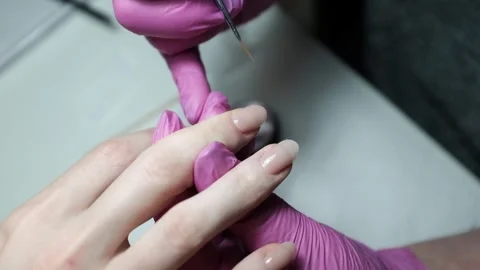Skilled nail technician applying nail polish or base coat, making a manicure. Stock Footage 326251634