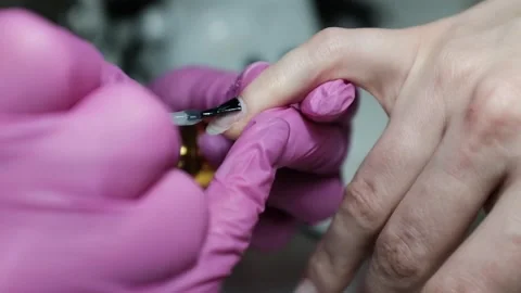 Skilled nail technician applying nail polish or base coat, making a manicure. Stock Footage 326251764