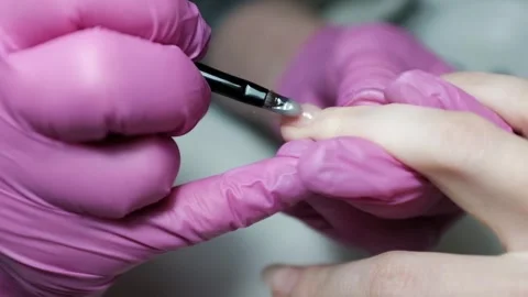 Skilled nail technician applying nail polish or base coat, making a manicure. Stock Footage 326251809