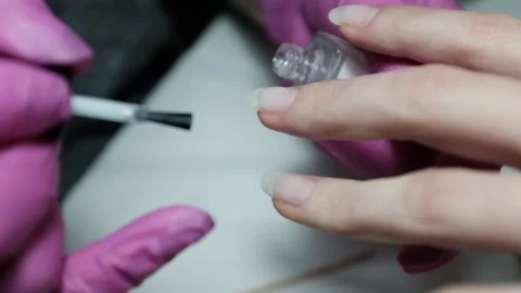 Skilled nail technician applying nail polish or base coat, making a manicure. Stock Footage 326251831