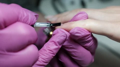 Skilled nail technician applying nail polish or base coat, making a manicure. Stock Footage 326251855