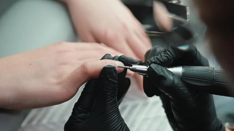 A skilled nail technician works on a client's nails using an electric tool in a Video stock 339093793