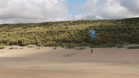 Skilled paraglider pilot soaring just above beach along dune Stock Footage 327334752
