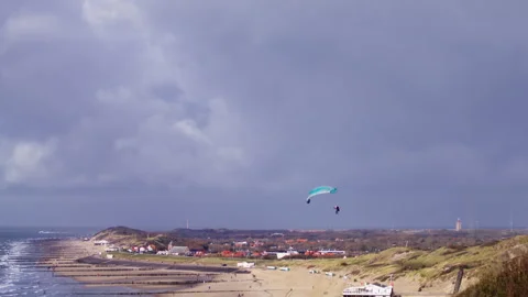 Skilled paraglider spiralling downward over Dutch beach during coastal soaring 動画素材 325832185