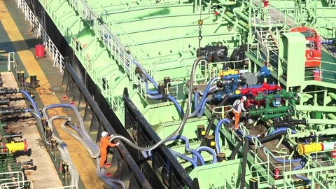Skilled people connect different coloured oil transfer hoses Stock Footage 113196917