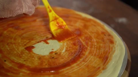 Skilled pizza maker puts ketchup on thick dough piece smearing sauce. Stock Footage 159370049