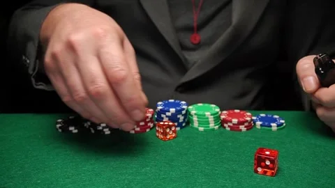 Skilled player stacking poker chips and rolling dice on green felt table in a Stock Footage 327137398