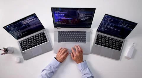 Skilled Programmer Creating Web Software On Multiple Laptops At Office. Foto stock