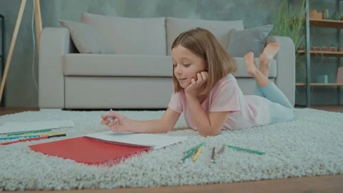 Skilled schoolkid lying floor draw pencil diy postcard in living room Stock Footage 166678724