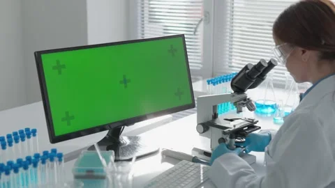A skilled scientist analyzes samples with a microscope in a modern lab, using a Stock Footage 317025902