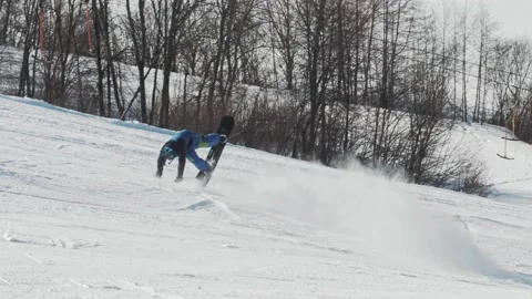 Skilled snowboarder performs a tripod trick and carves down the hill Stock Footage 221745422