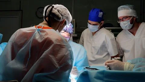 Skilled surgeons in a bright operating room perform a life saving procedure Stock Photos