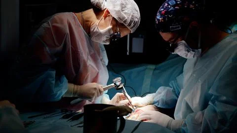 Skilled surgeons perform delicate operation in dimly lit room, showcasing Stock Photos