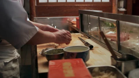 Skilled sushi chef preparing and serving pieces of sushi to customers in small s Stock Footage 199463444