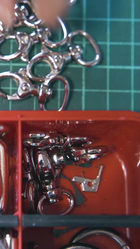Skilled tailor takes silver clasps from red container close Stock Footage 317087631