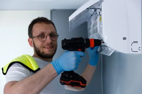 A Skilled Technician Installing an Air Conditioning Unit Using a Cordless Drill Stock Photos