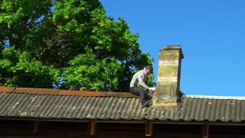 A skilled technician is performing chimney repair work on a roof, all while enjo Stock Footage 344902145