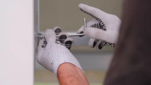 Skilled technician using a wrench to tighten screws on a cabinet door Stock Footage 318710811