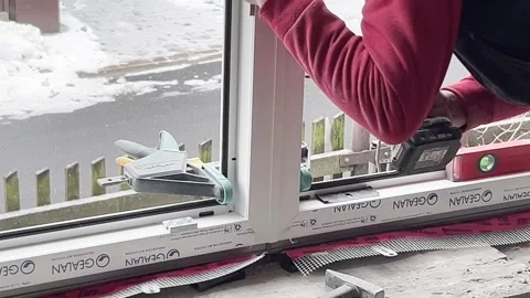 Skilled tradesman using drill tool installing new window frame build Stock Footage 327626767