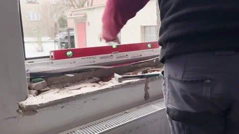 Skilled tradesman using level tool installing new window frame build Stock Footage 327690332