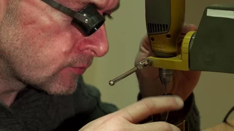 Skilled watchmaker meticulously perforating a watch piece Stock Footage 311951399