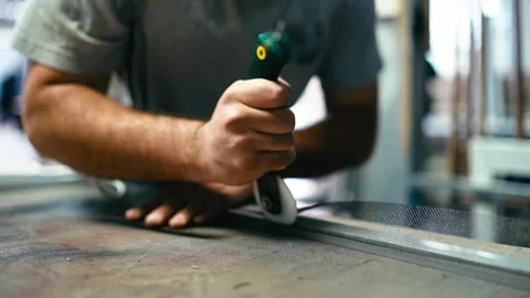 Skilled worker assembling aluminum profile for window screen. Using roller Stock Footage 279457179