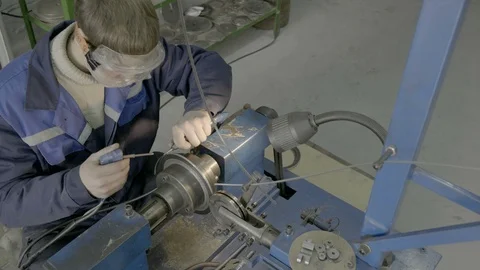 A skilled worker in blue measures the dimensions of a part using a vernier Stock Footage 127028251