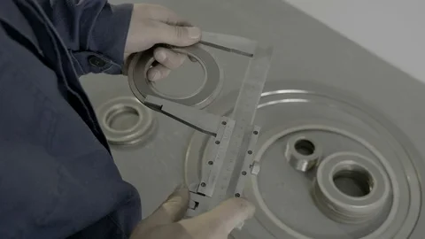 A skilled worker in blue measures the dimensions of a part using a vernier Stock Footage 127048004