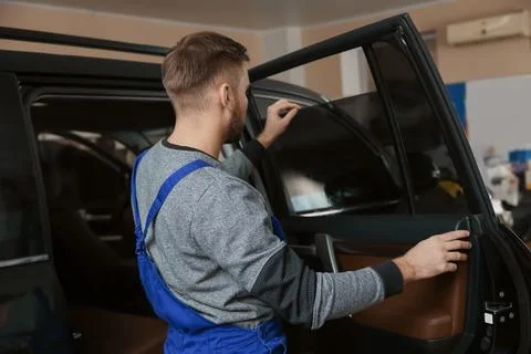 Skilled worker checking tinted car window in shop Stock Photos