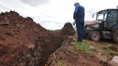 Skilled worker controls burying of trench with bulldozer 库存影片 142307419